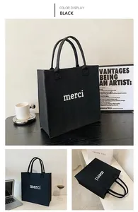 Detailed view of black felt tote bag with white merci print and minimalist design