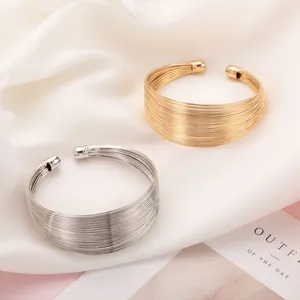 Exquisite detail of gold and silver multi-strand wide open cuff bracelets on white silk