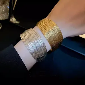 Close-up detail of luxurious gold and silver textured wide-sided open bracelets on wrist