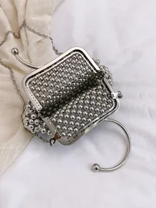 Macro view of handmade silver beaded bridal handbag with metallic handle and chain