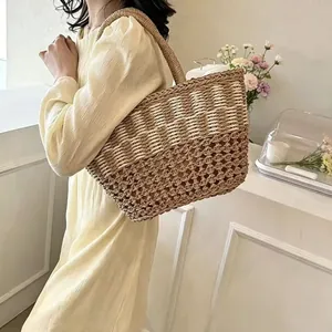Handwoven straw tote bag with H design carried by a model for a stylish vacation look