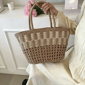 Close-up of a stylish handcrafted straw woven beach tote bag held by hand in lifestyle setting.