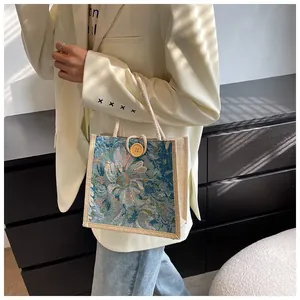 Detailed shot of a woven floral tapestry handbag with rope handles and a wooden button.