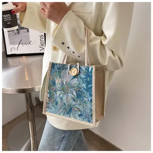Close-up detail of blue floral jacquard tote bag with rope handles and wooden button