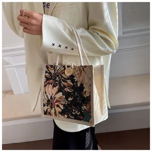 Detail of a vintage floral tapestry tote bag with rope handles and wooden button