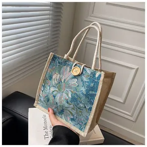 Detailed view of blue floral jacquard tote bag with rope handles and wood button