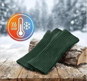 Close-up of dark green knitted long fingerless arm warmers on a snowy wooden surface