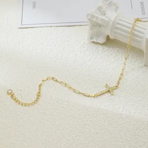 Close-up of elegant gold paperclip chain bracelet with sparkling CZ-paved cross.