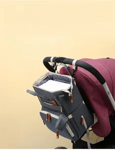 Detail showing gray diaper bag hanging on stroller handle with functional hooks