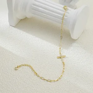 Detailed view of elegant gold paperclip chain bracelet featuring a shimmering zircon cross