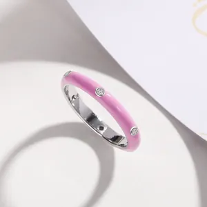 Detailed view of a minimalist pink enamel band ring set with three sparkling zircons.