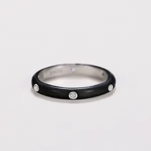 Close-up detail of a minimalist black enamel ring with embedded sparkling zircons.