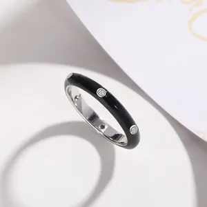 Detailed view of minimalist black enamel ring featuring circular zircon inlays.