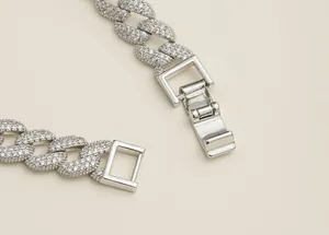 Détail de bracelet à maillons cubains argentés avec strass complets et fermoir pliant