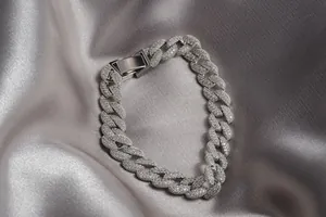 Gros plan d'un bracelet cubain argenté serti de strass brillants sur fond de soie.