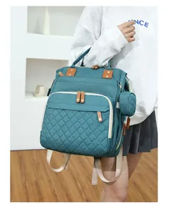 Lifestyle shot of a teal quilted diaper backpack worn by a model in a modern interior.