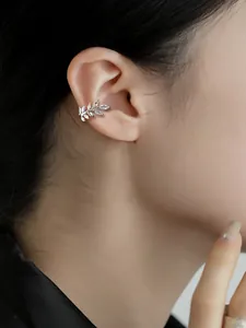 Detailed view of a sparkling silver zircon leaf ear cuff worn on model's ear bone