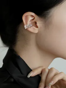 Detailed macro view of a sparkling leaf ear cuff with cubic zirconia on a female ear
