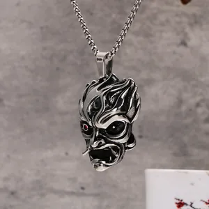 Vue détaillée d'un pendentif masque de démon vintage en acier inoxydable avec yeux rouges