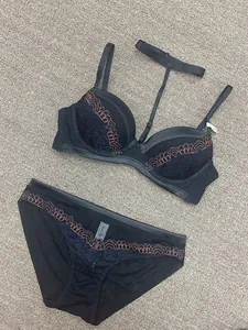 Gros plan d'un ensemble de lingerie en dentelle noire avec broderies orange élégantes.