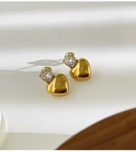 Detail view of gold heart stud earrings with sparkling cubic zirconia inlay.