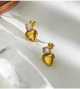 Close-up of golden heart stud earrings with sparkling cubic zirconia inlay for women