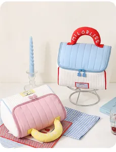 Detail of quilted house-shaped cosmetic bags with MILOBLISS embroidered handles.