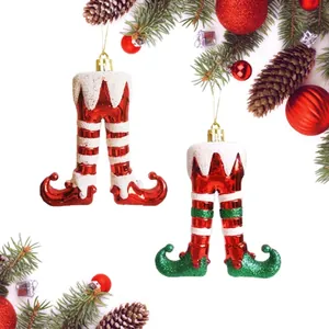 Close-up of red and green painted Christmas elf leg hanging ornaments on a tree.