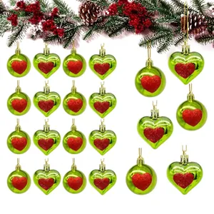 Detail view of festive green Christmas ball and heart ornaments with red glitter heart patterns