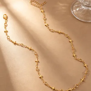Détail d'un collier doré avec pendentifs étoiles à quatre branches et zircons