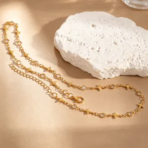 Détail d'un collier étoile à quatre branches doré avec cristaux sur pierre décorative.