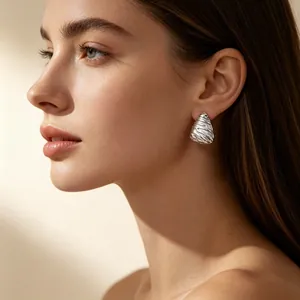 Close-up of retro embossed irregular triangle stainless steel earring on female model.