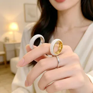 Primo piano di eleganti anelli in acciaio con intarsio di perle sulla mano di una modella.