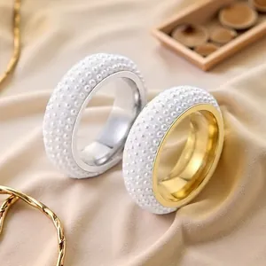 Dettaglio di anelli in acciaio inox con cinque file di perle nei colori oro e argento.