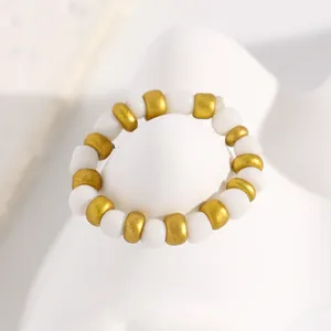 Detailed macro view of an elegant white and gold beaded acrylic pearl ring on a white prop.