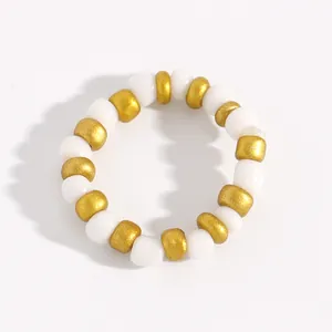 Detailed top view of a white and gold acrylic beaded ring on a white surface