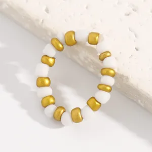 Macro view of an elastic beaded ring featuring alternating white and matte gold beads