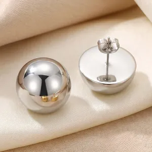 Detailed view of silver stainless steel hemisphere stud earrings on silk fabric