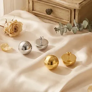 Close-up of gold and silver stainless steel hollow hemisphere stud earrings on silk