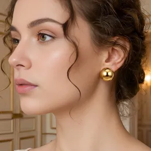 Model wearing large golden hollow hemisphere stud earrings in a polished finish