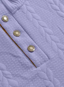 Detailed close-up of purple jacquard quilted fabric with embossed metal button detail