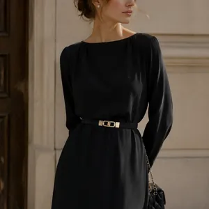 Close-up of a minimalist black thin belt with a gold double-ring buckle on a dress.