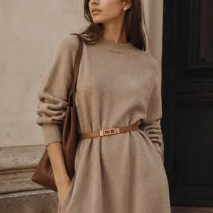 Elegant beige knitted sweater dress with brown leather belt and shoulder bag accessory.