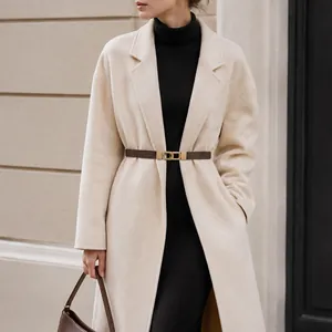 Elegant brown elastic waist belt with gold buckle on a beige coat detail view.