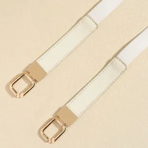 Detailed view of white elastic slim belt with gold buckle and cream leather ends