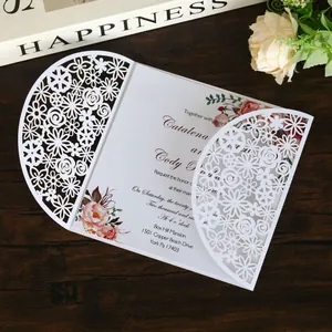 Detail of elegant laser-cut floral wedding invitation on a wooden background.