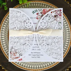 Elegant white laser-cut floral wedding invitation card with cream silk ribbon bow