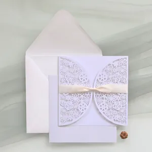Elegant laser-cut white wedding invitation with floral pattern and ribbon detail
