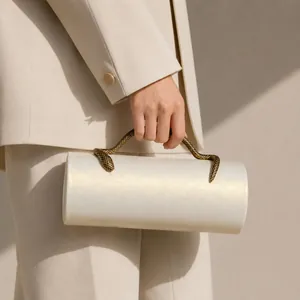 Detailed view of an elegant cream PU cylinder clutch with an antique bronze snake handle