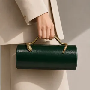 Detailed view of a luxurious dark green cylindrical evening clutch with gold snake handle
